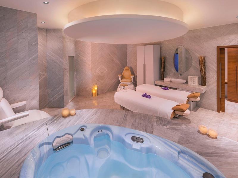 Moderner Wellnessraum mit Whirlpool, zwei Massageliegen und entspannender, gedämpfter Beleuchtung.