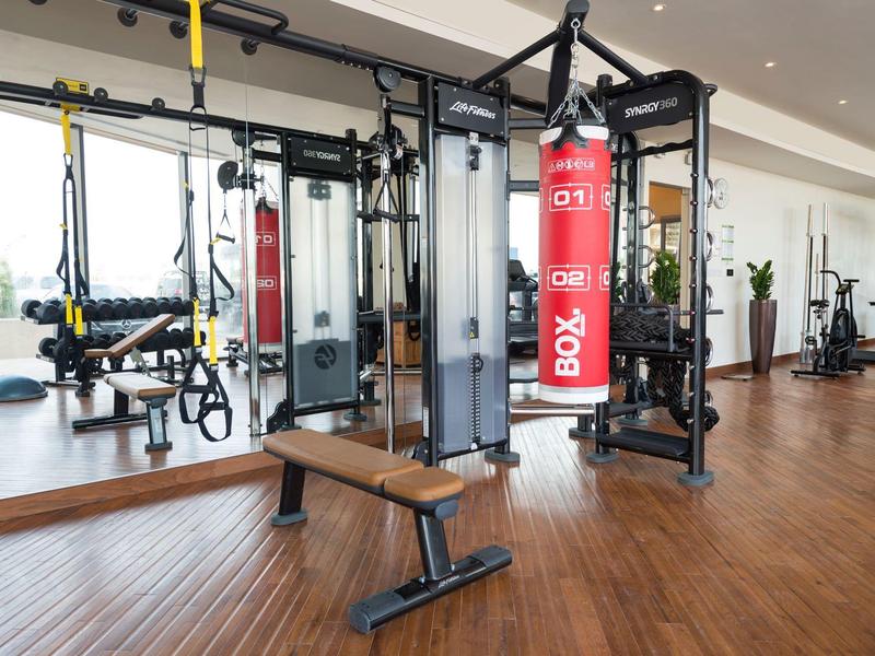 Moderne Fitnessstudio mit Holzfußboden und vielfältigen schwarzen Trainingsgeräten.