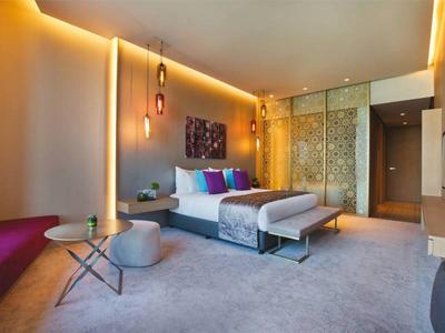 Modernes Schlafzimmer mit großem Bett, weichem Teppich und warmen indirekten Lichtern.