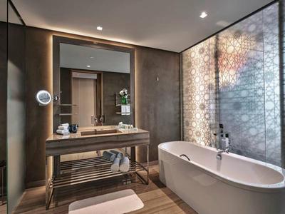 Moderner Badbereich mit frei stehender Badewanne, Holz-Waschtisch und dekorativer Glaswand.