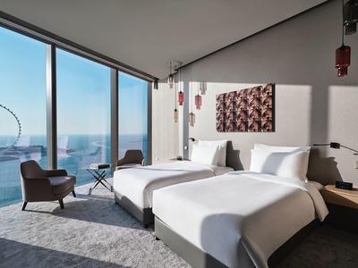 Modernes Hotelzimmer mit zwei Betten und großem Panoramafenster mit Ausblick auf Stadt und Riesenrad.