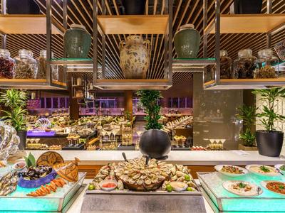 Buffet mit frischem Obst, Gebäck und dekorativen Pflanzen in warm beleuchtetem Raum.