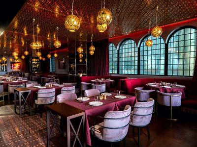 Elegantes Restaurant mit runden Lampen, Samtpolsterstühlen und großen Bogenfenstern.