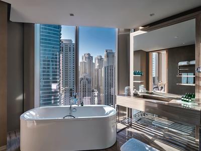Moderne Badezimmereinrichtung mit freistehender Badewanne und großem Spiegel vor Fenster mit Stadtblick.
