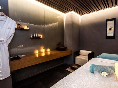 Eleganter Wellnessraum mit Massageliege, weichen Handtüchern, Kerzenlicht und ruhiger Atmosphäre.