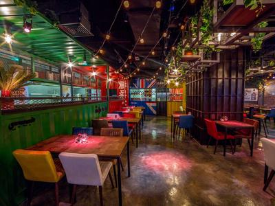 Cozy restaurant with colorful chairs, wooden and metal furniture, and warm lighting.