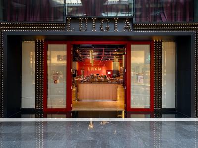 Entrada de un hotel elegante con puertas rojas abiertas y recepción moderna en el interior.