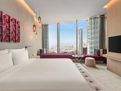 Habitación de hotel moderna con cama grande, vista a la ciudad e interior elegante a la luz del día.