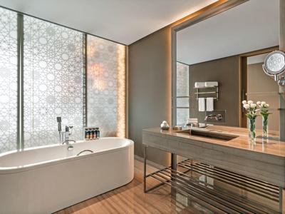 Baño moderno con bañera independiente, espejo grande y suelo de madera.