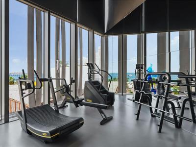 Modern fitness equipment in a bright gym with large windows and sea view.