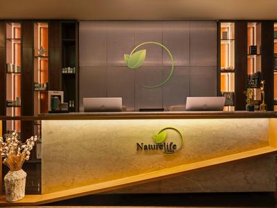 Recepción moderna con mostrador iluminado y estantes con decoraciones en un hotel elegante.