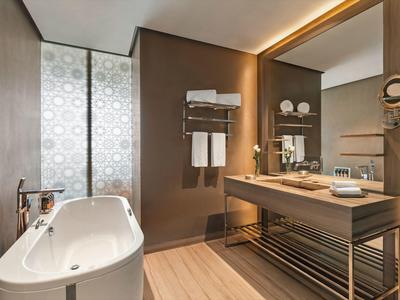 Baño moderno con bañera independiente, gran espejo y lavabo de madera.