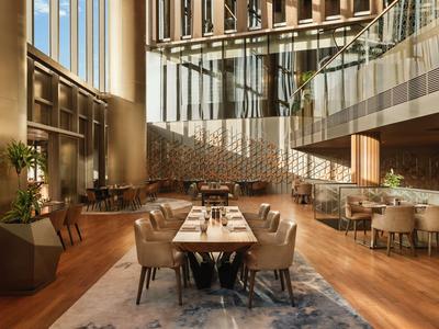 Elegant dining room with wooden flooring, cozy chairs, and large windows in a hotel.