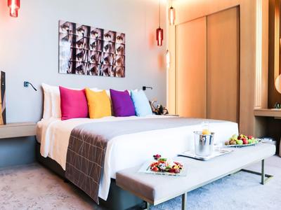 Modernes Schlafzimmer mit großem weißem Bett, bunten Kissen und minimalistischem Dekor.
