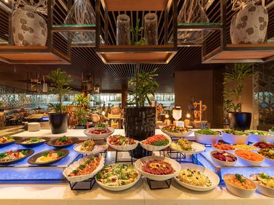 Buffet mit vielfältigen Speisen und dekorativen Pflanzen in einem eleganten Hotelrestaurant.