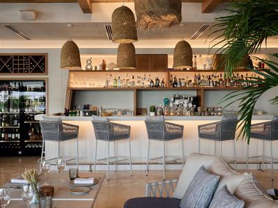 Moderner Hotelbarbereich mit Holztheke, Hockern und organisch geformten Hängeleuchten.