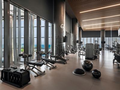Moderner Fitnessraum mit großen Fenstern, vielseitigen Geräten und Trainingsbällen in einem Hotel.