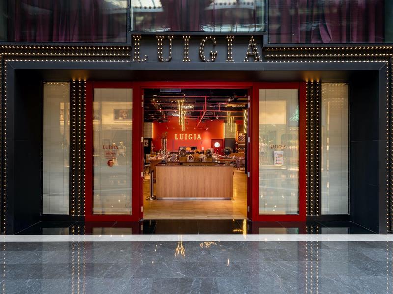 Entrada de un hotel elegante con puertas rojas abiertas y recepción moderna en el interior.