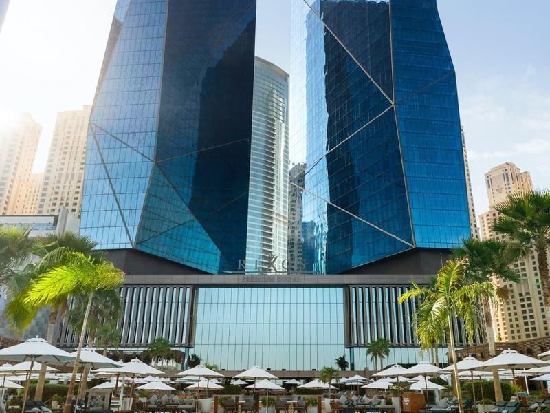 Rascacielos modernos detrás de una piscina con tumbonas y sombrillas en un hotel.