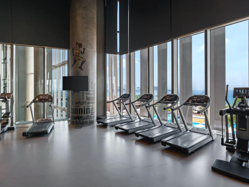 Gimnasio moderno con cintas de correr frente a grandes ventanas y vista despejada al exterior.