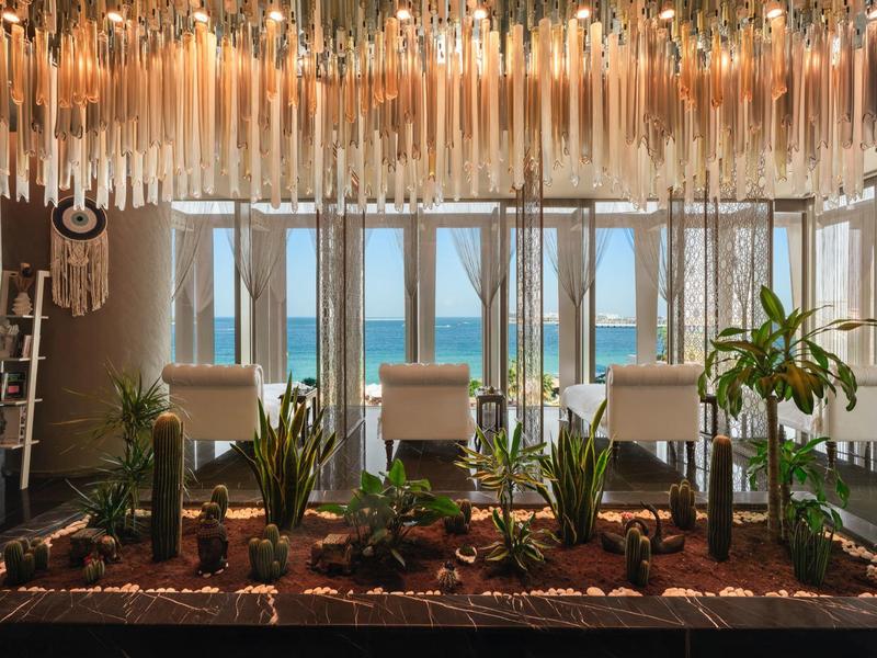 Área interior con gran ventanal, jardinera con plantas e iluminación moderna con vista al mar.
