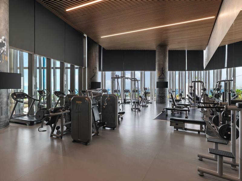 Gimnasio moderno con equipos y grandes ventanas en un hotel.