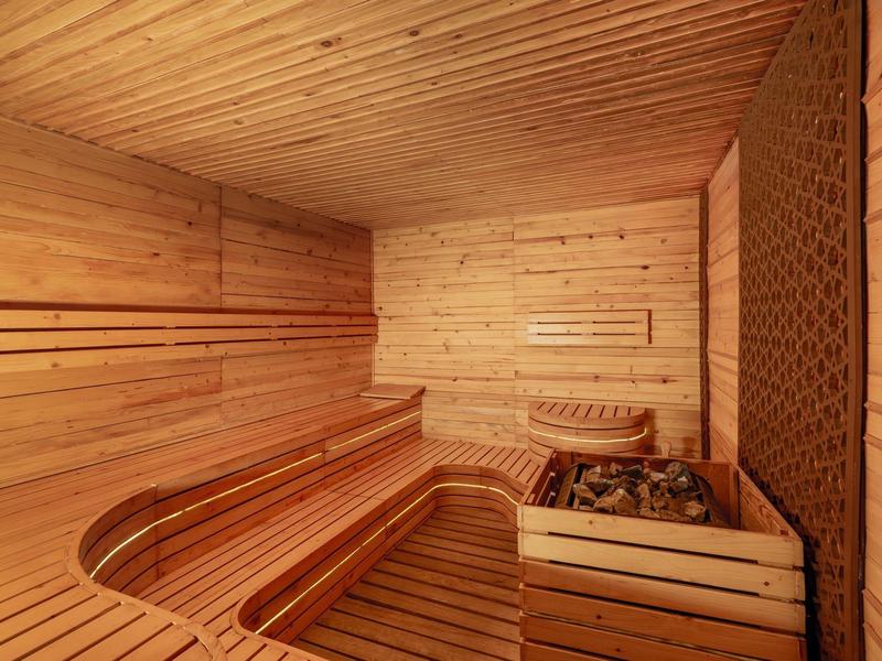 Sauna interior de madera con bancos curvos y calentador de piedras para relajación
