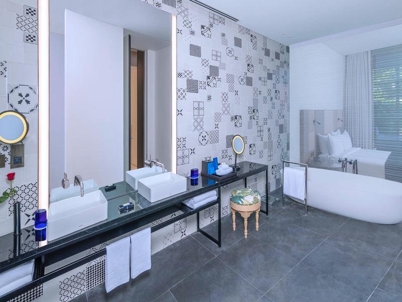 Modernes Badezimmer mit freistehender Badewanne, Spiegeln und stilvollem Waschbeckenbereich.