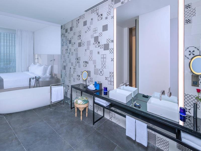 Modernes Badezimmer mit freistehender Badewanne, großem Spiegel und stilvollen Fliesen an der Wand.