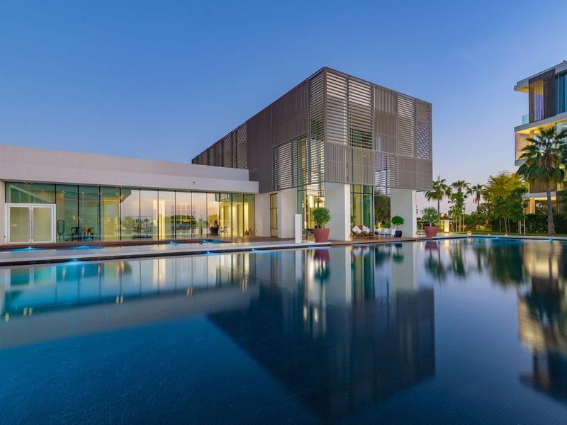 Modernes Hotelgebäude mit großem Pool und klarer Spiegelung bei Dämmerung