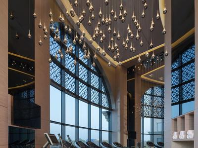 Moderne sportschool met meerdere loopbanden voor grote ramen en decoratieve plafondlampen.