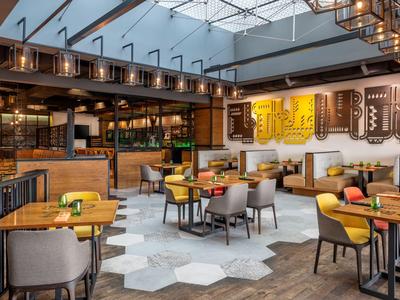 Modern restaurant met houten meubels, tapijtvloer en glazen dak