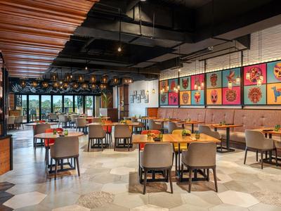 Modern hotelrestaurant met kleurrijke kunstwerken, houten accenten en veel zitplaatsen.