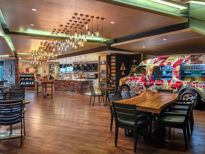 Moderne hotelbar met houten vloer, tafels, stoelen en kleurrijke wanddecoratie.