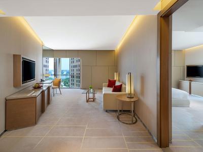 Světly hotelový pokoj s moderním designem, televizí s plochou obrazovkou a posezením.