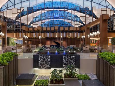 Moderní hotelová restaurace se skleněnou kopulí, dřevěnými trámy a stylovými rostlinnými aranžmá.