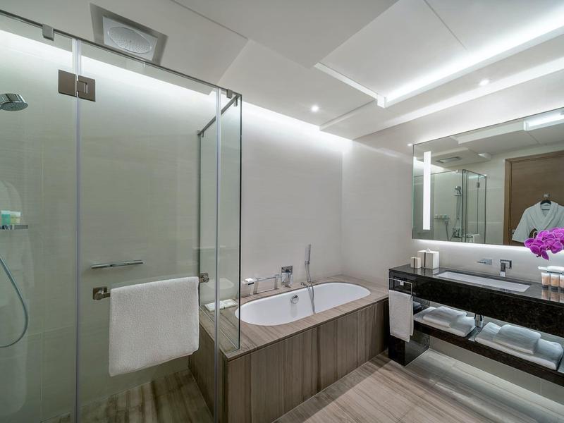 Moderne badkamer met bad, glazen douche en grote spiegel boven de wastafel.