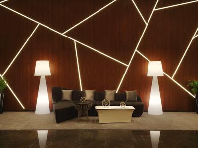 Área de lounge de hotel de diseño moderno con sofás, mesa, lámparas de pie y líneas decorativas en la pared.