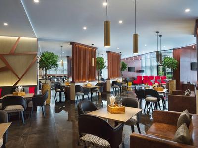 Moderně zařízený restauranční prostor se stoly, židlemi a pohovkami za teplého osvětlení.