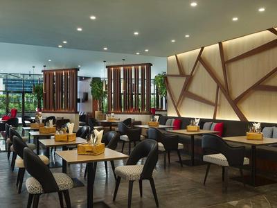 Moderner Restaurantinnenraum mit Holztischen, gepolsterten Stühlen und dekorativer Wandbeleuchtung.