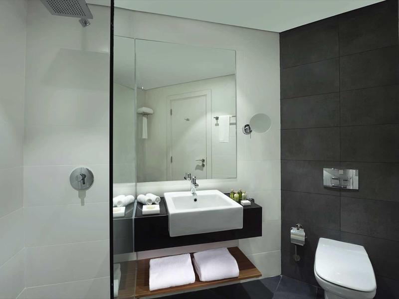 Baño moderno con lavabo, espejo, inodoro y pared oscura en la habitación del hotel.