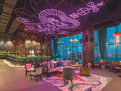 Modernes Hotelrestaurant mit farbenfroher Beleuchtung und gemütlichen Sitzbereichen.