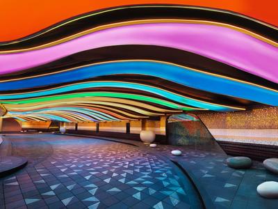 Moderne Halle mit wellenförmiger Decke in leuchtenden Farben und organischen Steinstrukturen.