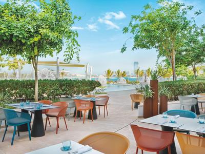 Outdoor-Restaurantbereich mit bunten Stühlen und Blick auf Meer und barfuß Strand