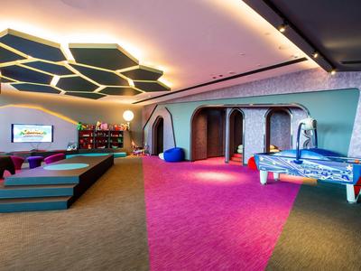 Moderner Spielraum mit Kicker, Sitzkissen, Teppichboden und ungewöhnlicher Deckenbeleuchtung.