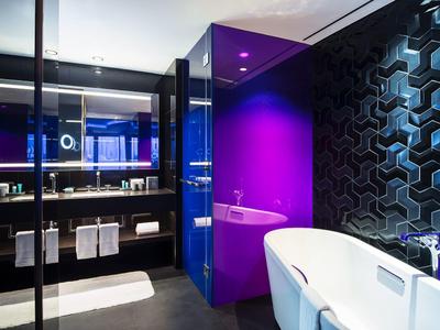 Moderner Badbereich mit freistehender Badewanne, schwarzer 3D-Wandstruktur und violetter Wand.