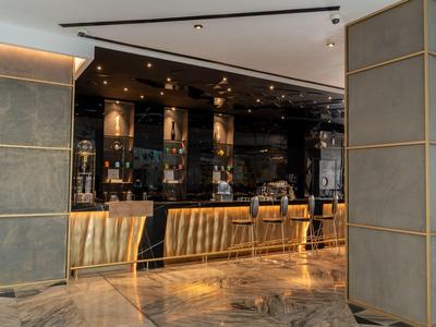 Elegante Hotelbar mit modernen Stühlen, beleuchtetem Tresen und poliertem Marmorboden.