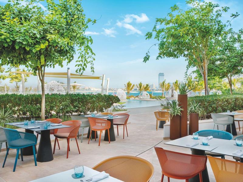 Outdoor-Restaurantbereich mit bunten Stühlen und Blick auf Meer und barfuß Strand