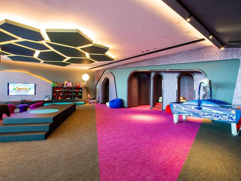 Moderner Spielraum mit Kicker, Sitzkissen, Teppichboden und ungewöhnlicher Deckenbeleuchtung.