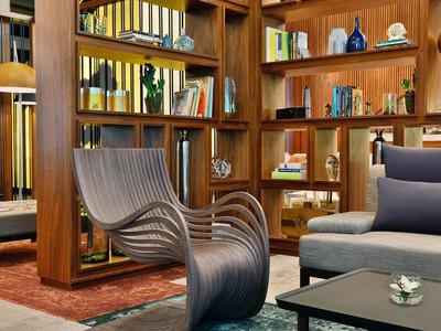Modern chair in front of a wooden bookshelf in a cozy hotel lounge area.